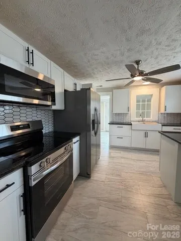 a large kitchen with stainless steel appliances kitchen island granite countertop a stove refrigerator and a microwave