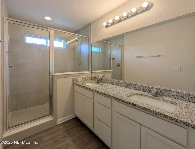 a bathroom with a granite countertop sink a large mirror and shower