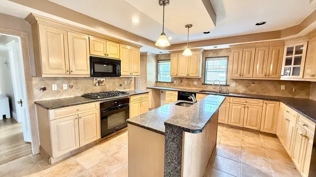 a kitchen with stainless steel appliances granite countertop a stove top oven a sink dishwasher a dining table and chairs with wooden floor