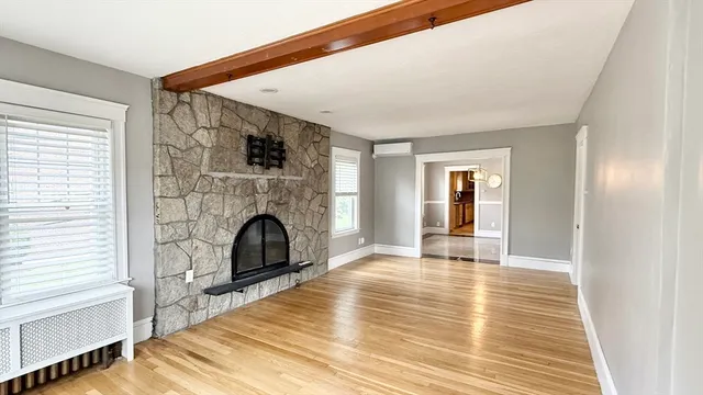a view of empty room with fireplace and wooden floor