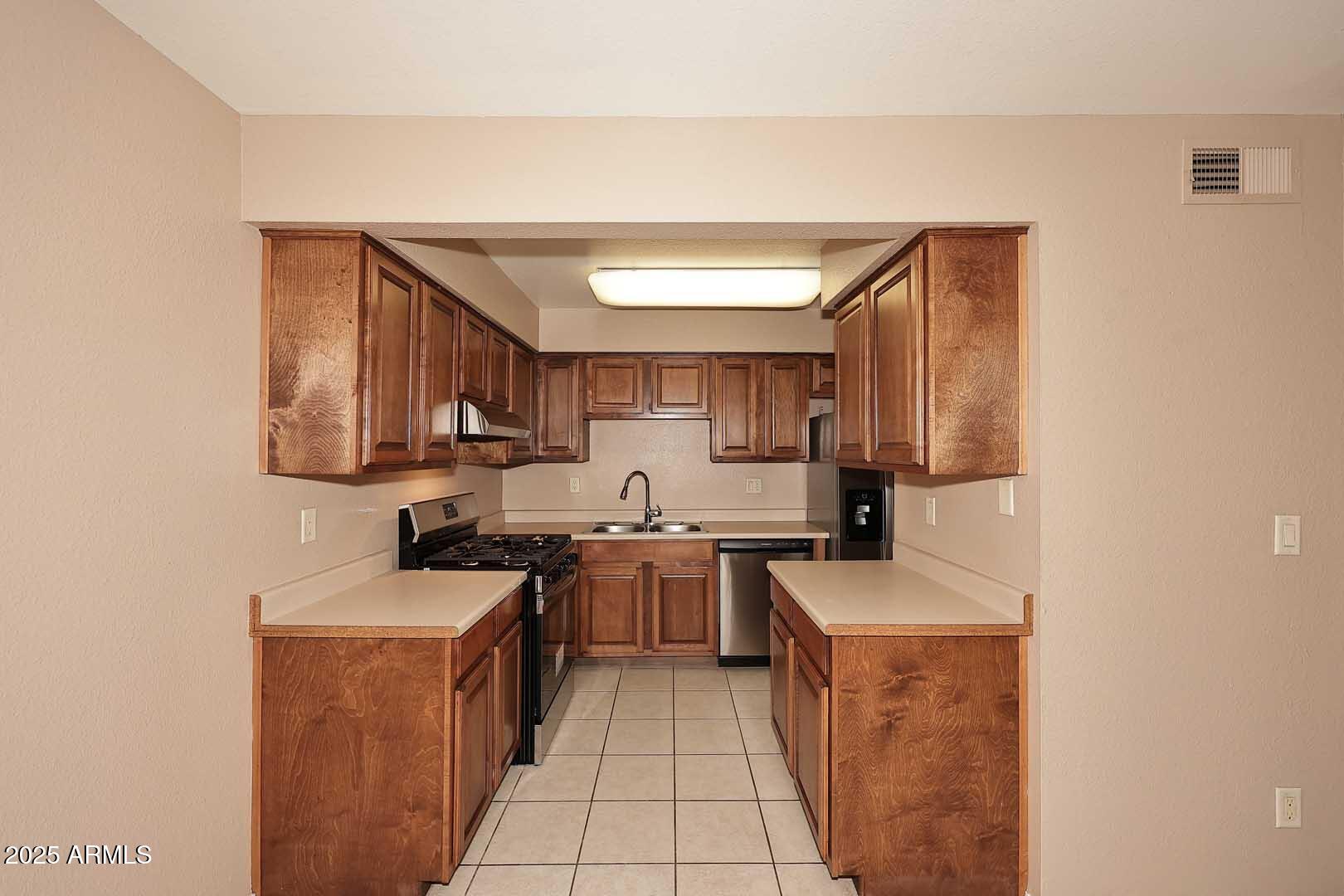 303 North Miller Road, Unit 1007 Scottsdale, AZ 85257 - Photo 12 of 28 a kitchen with a sink a stove top oven and cabinets