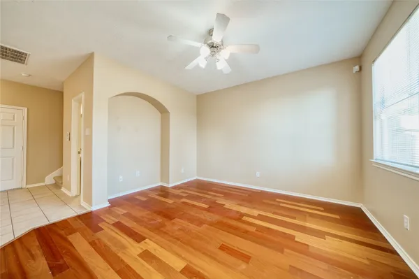 a view of an empty room with window and wooden floor