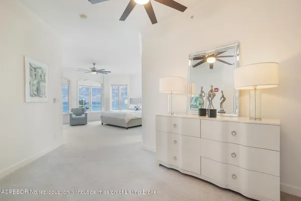 a spacious bedroom with a bed a lamp on dresser and a chandelier