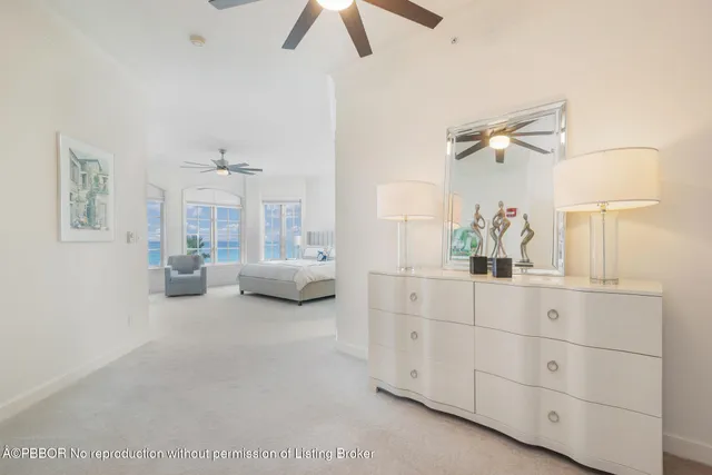 a spacious bedroom with a bed a lamp on dresser and a chandelier