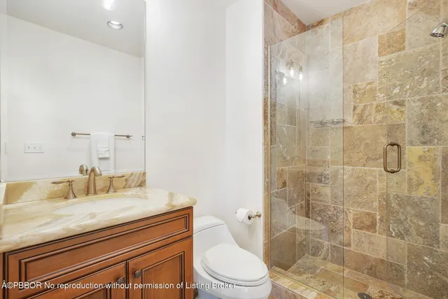 a bathroom with a granite countertop sink a toilet a mirror and shower