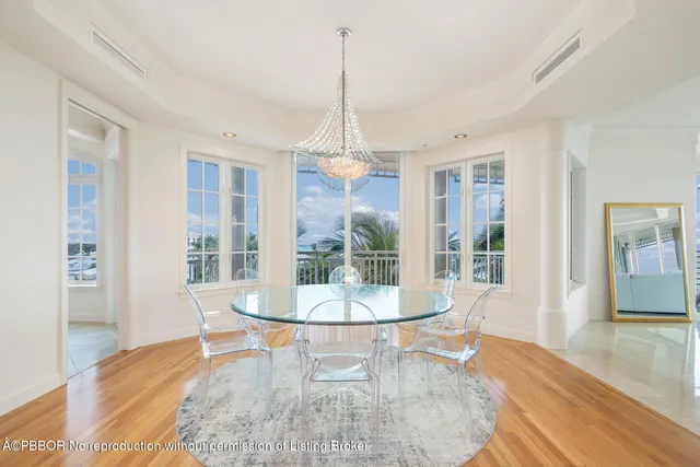 a dining room with wooden floor a chandelier a glass table and chairs