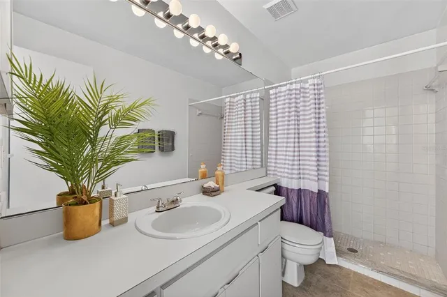 a bathroom with a granite countertop sink a toilet and mirror