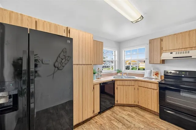a kitchen with stainless steel appliances a sink cabinets and a window