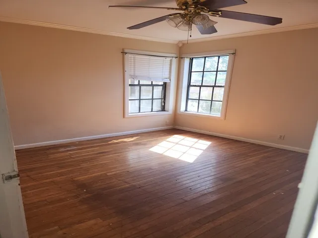 an empty room with wooden floor and windows