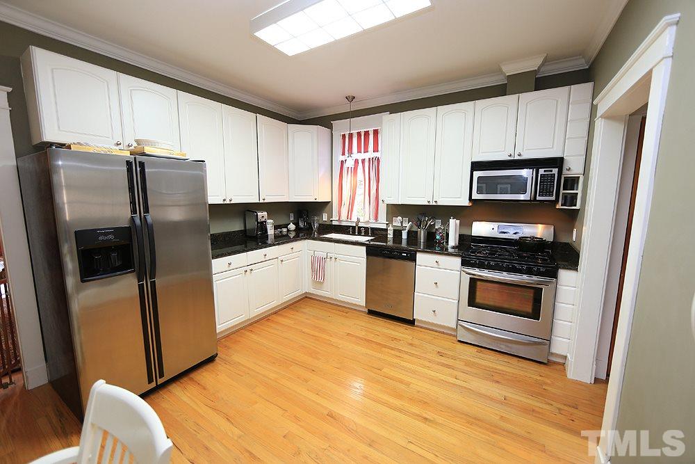 1802 Reaves Drive Raleigh, NC 27608 - Photo 4 of 22 a kitchen with granite countertop a refrigerator a sink a stove a microwave and cabinets
