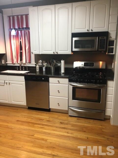 1802 Reaves Drive Raleigh, NC 27608 - Photo 9 of 22 a kitchen with stainless steel appliances granite countertop a stove a microwave and a white cabinets