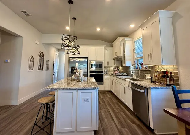 a kitchen with stainless steel appliances kitchen island granite countertop a stove and cabinets