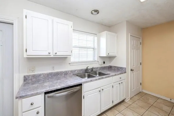 a kitchen with granite countertop white cabinets and a sink