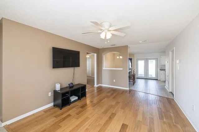 a view of a livingroom with a flat screen tv wooden floor and a ceiling fan