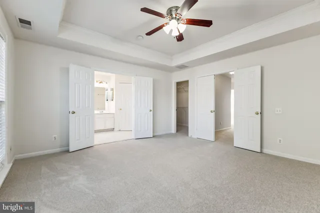 an empty room with closet and a ceiling fan