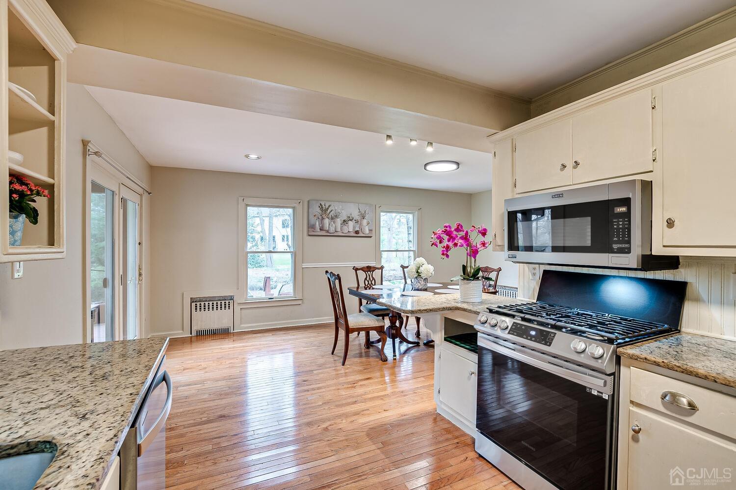 13 Herron Road Edison, NJ 08820 - Photo 23 of 51 a kitchen with stainless steel appliances granite countertop a stove top oven a sink dishwasher and a dining table with wooden floor