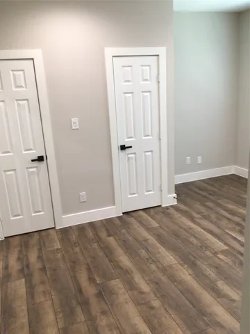 an empty room with wooden floor and mirror