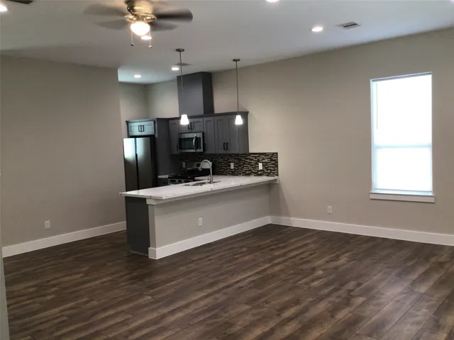 a kitchen with stainless steel appliances a refrigerator and a hard wood floor