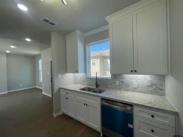 a kitchen with granite countertop white cabinets and sink
