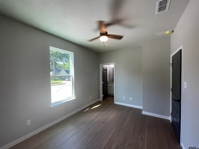 an empty room with wooden floor closet and windows