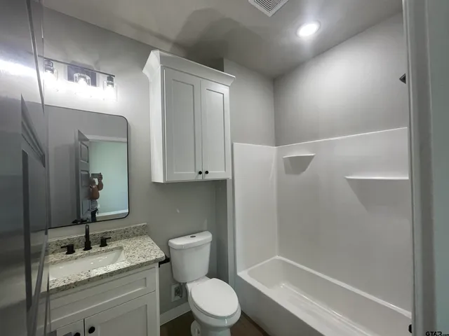 a bathroom with a granite countertop sink toilet a mirror and shower