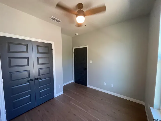 a view of an empty room with a dresser wooden floor and closet