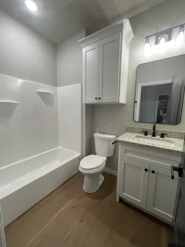 a bathroom with a toilet a sink a tub and mirror