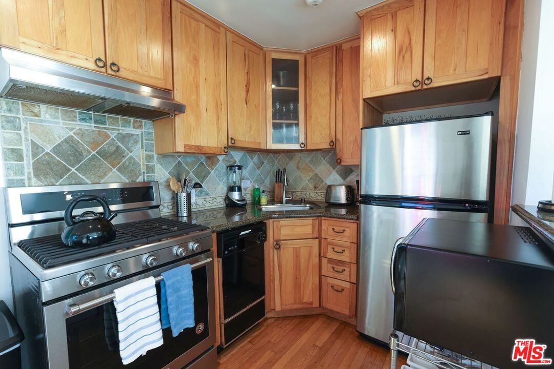 2101 Ocean Avenue, Unit 1 Santa Monica, CA 90405 - Photo 8 of 11 a kitchen with granite countertop stainless steel appliances and wooden cabinets