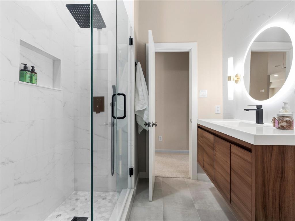 1615 Roma Lane Allen, TX 75013 - Photo 27 of 36 Contemporary bathroom featuring a spacious glass-enclosed shower with a rainfall showerhead, white marble-look wall tiling, and a hexagon-tiled shower floor