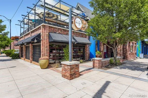 a view of a building with sitting area and large trees