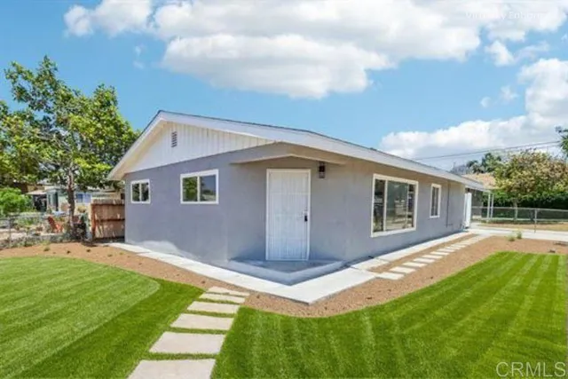 a view of a yard in front of a house with plants and large tree