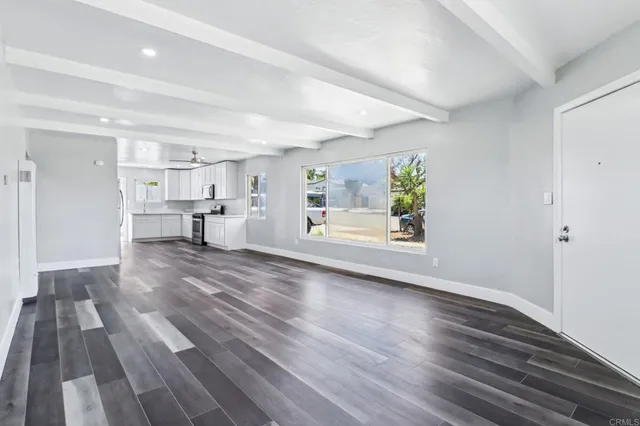 a view of kitchen and empty room with wooden floor