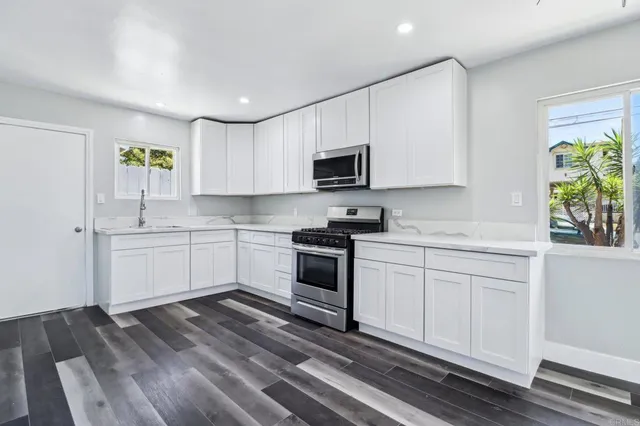 a kitchen with stainless steel appliances granite countertop a stove a sink and a microwave