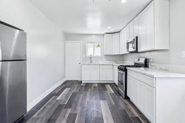 a view of a kitchen with a sink and dishwasher a refrigerator with wooden floor