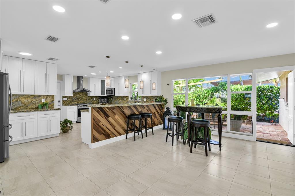 1616 Southeast 4th Street Deerfield Beach, FL 33441 - Photo 21 of 52 a kitchen with stainless steel appliances dining table chairs and white cabinets