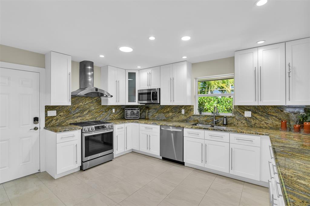 1616 Southeast 4th Street Deerfield Beach, FL 33441 - Photo 25 of 52 a kitchen with stainless steel appliances granite countertop a stove sink and cabinets