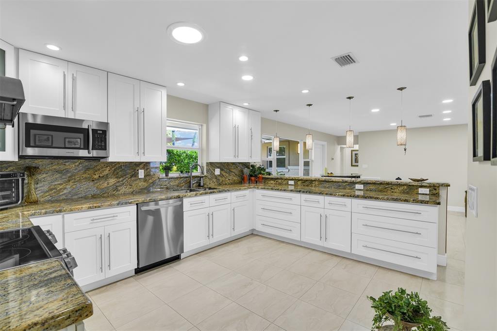 1616 Southeast 4th Street Deerfield Beach, FL 33441 - Photo 28 of 52 a large kitchen with granite countertop lots of white stainless steel appliances and cabinets