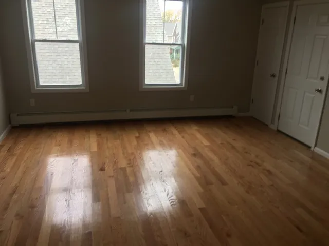 an empty room with wooden floor and windows