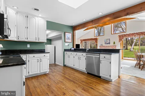 a kitchen with stainless steel appliances granite countertop a refrigerator a stove a sink a dining table and chairs with wooden floor