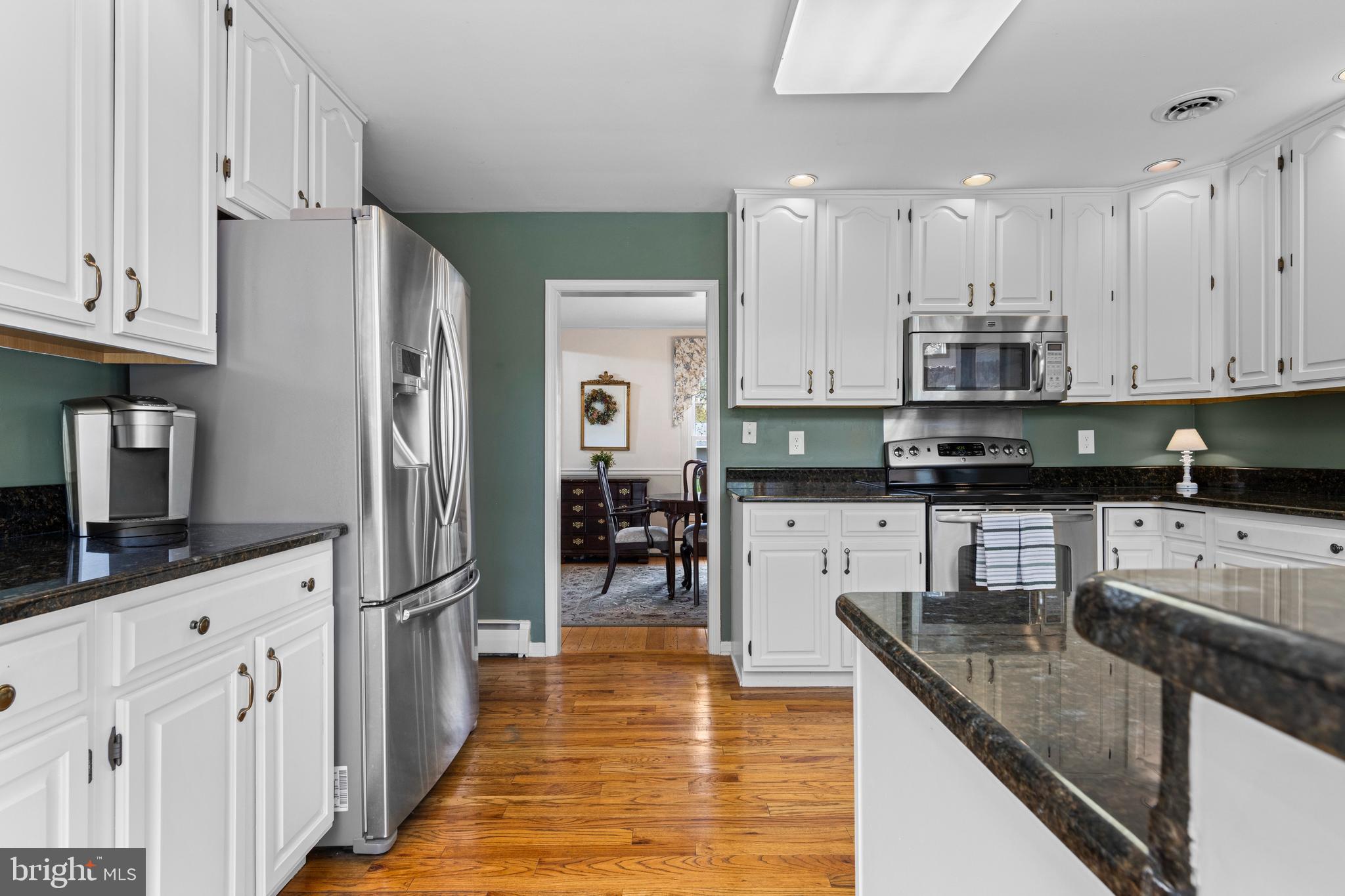 292 Old State Road Berwyn, PA 19312 - Photo 14 of 43 a kitchen with stainless steel appliances granite countertop a refrigerator a stove a sink a dining table and chairs with wooden floor
