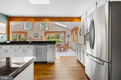 a large white kitchen with stainless steel appliances granite countertop a refrigerator a stove and a sink