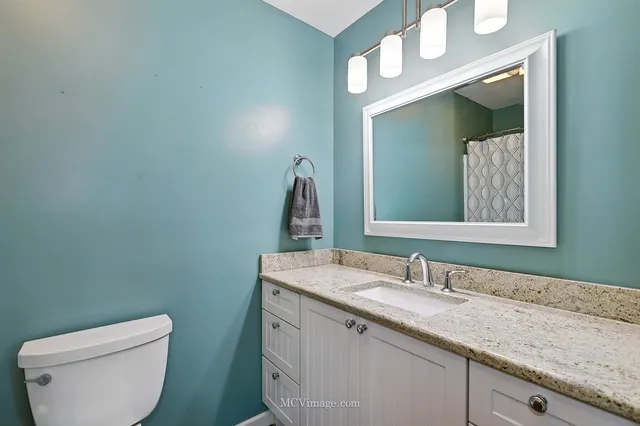 a bathroom with a granite countertop toilet sink and mirror