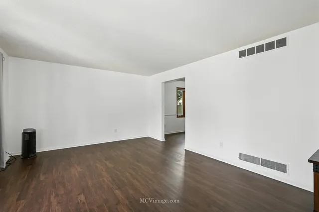 a view of an empty room with wooden floor