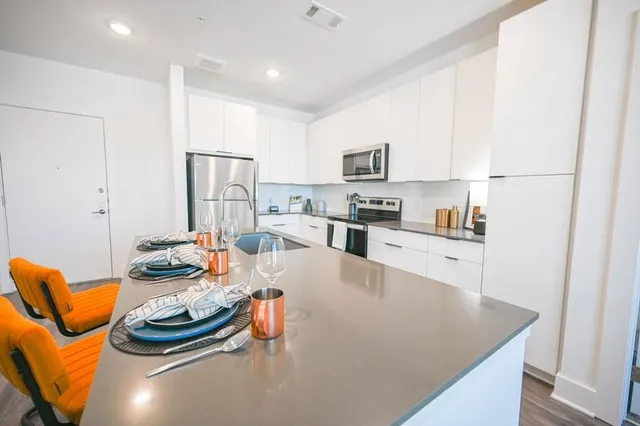 a kitchen with stainless steel appliances kitchen island granite countertop a stove and white cabinets