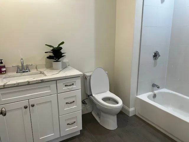 a bathroom with a granite countertop toilet sink and mirror