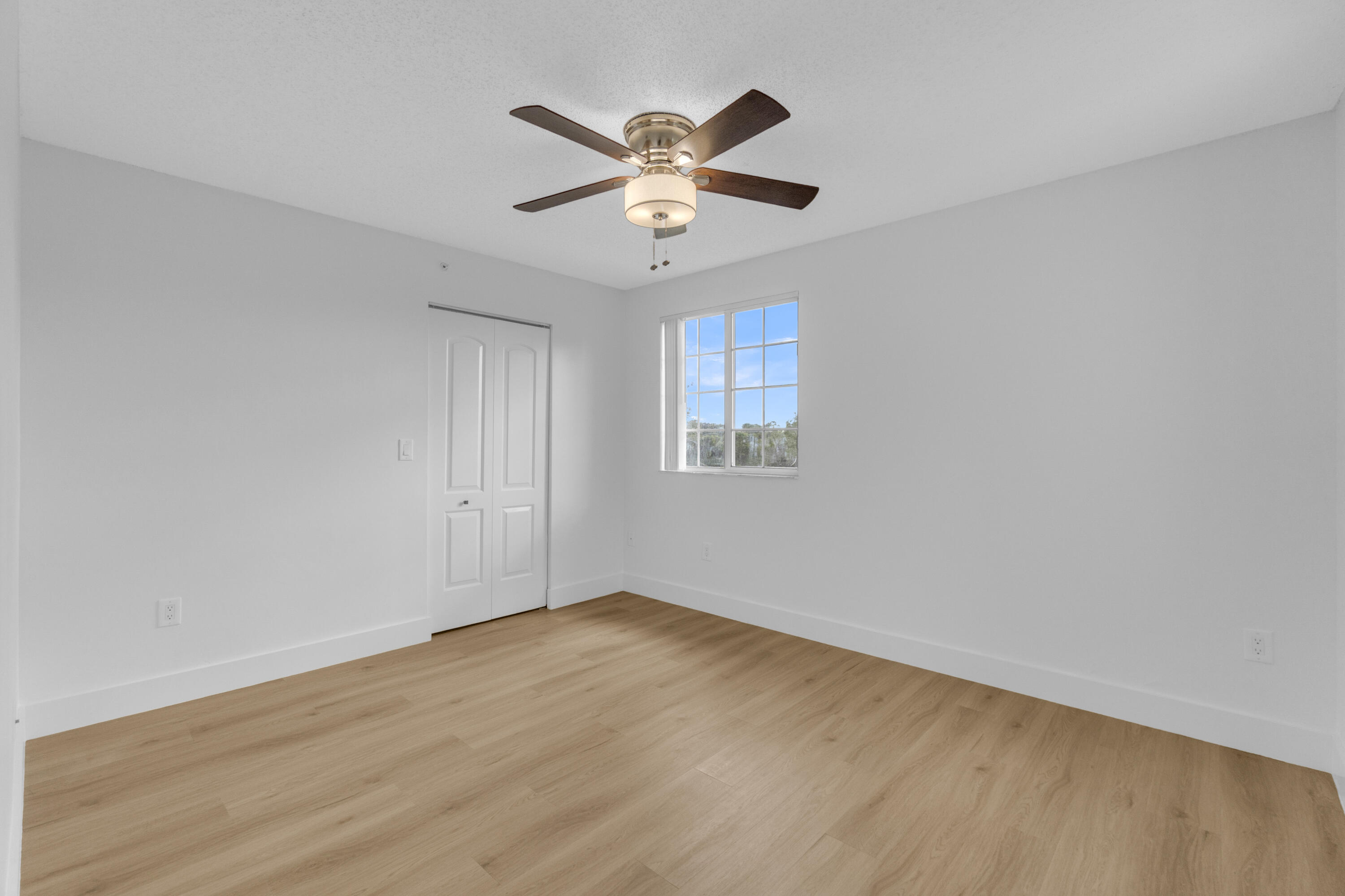 400 Crestwood Court North, Unit 420 Royal Palm Beach, FL 33411 - Photo 20 of 44 an empty room with wooden floor ceiling fan and windows