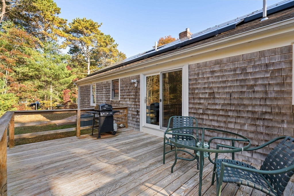 83 Dolar Davis Road Barnstable, MA 02632 - Photo 25 of 36 a view of a patio with table and chairs with wooden floor and fence