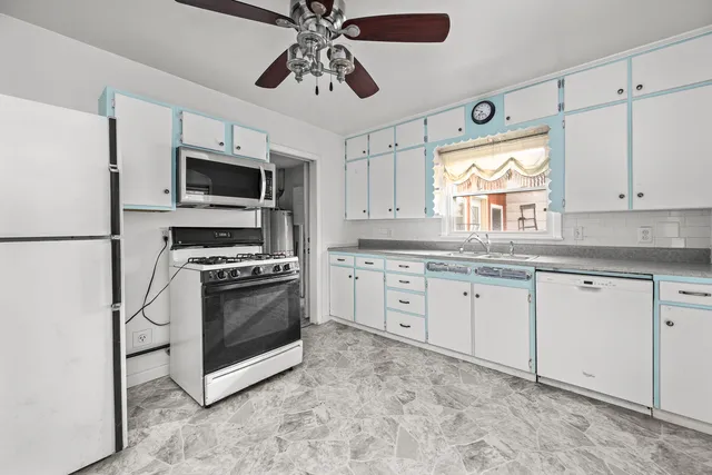 a kitchen with granite countertop a sink stainless steel appliances and white cabinets
