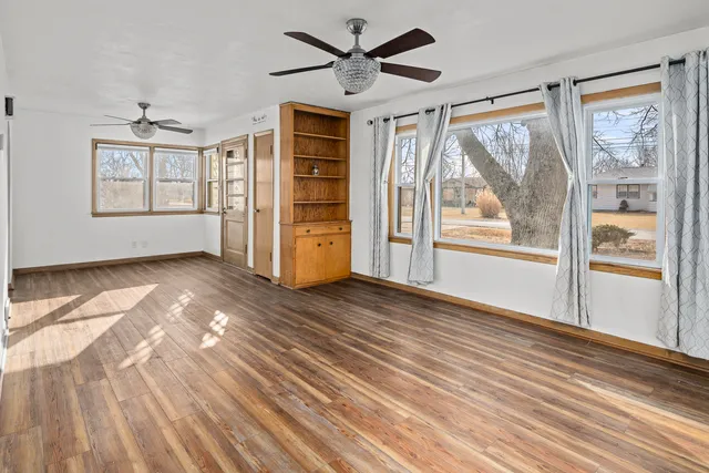 a view of empty room with wooden floor and fan