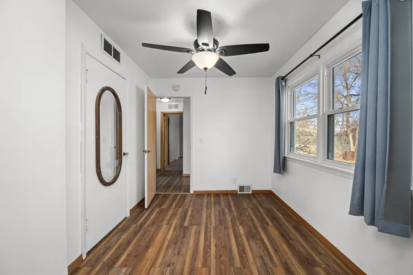 a view of a room with wooden floor fan and windows